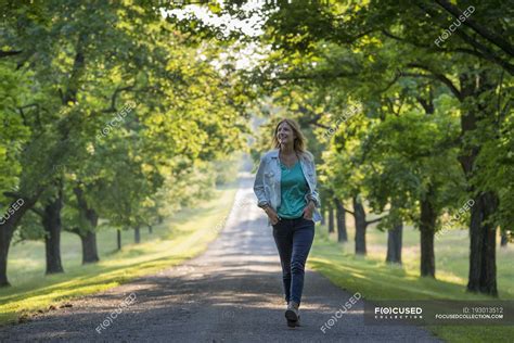 Persona mayor caminando en un parque soleado con naturaleza