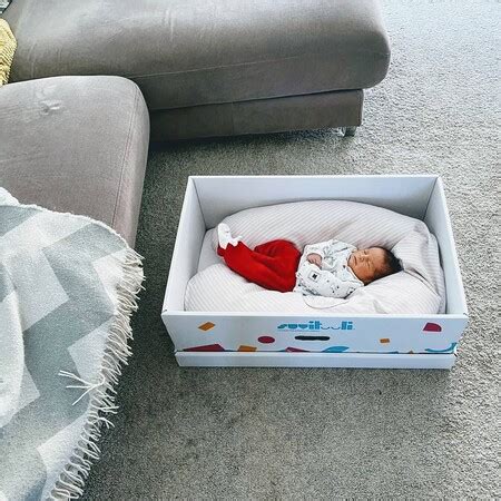 Familia feliz utilizando la caja de maternidad finlandesa como cuna
