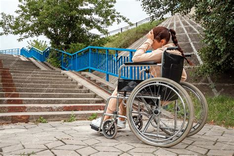 fotografía de una persona en silla de ruedas enfrentando una barrera arquitectónica, como una acera sin rampa o un escalón