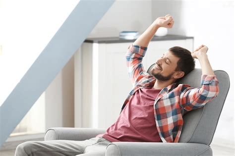 Persona mayor relajándose y sonriendo en un sillón de masaje ergonómico en un entorno hogareño