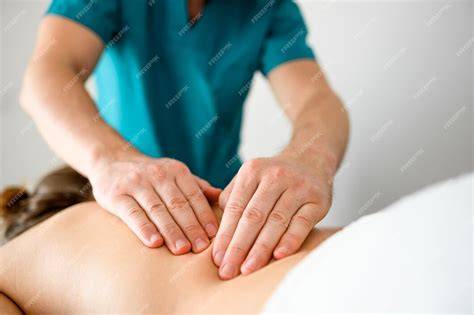 Foto de un terapeuta aplicando un masaje suave en la espalda de un adulto mayor