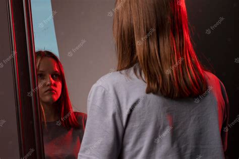 Foto de una joven adolescente pensativa mirando su reflejo