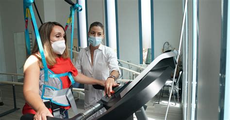 Fotografía de un paciente utilizando un dispositivo de soporte de peso corporal durante una sesión de rehabilitación de la marcha.