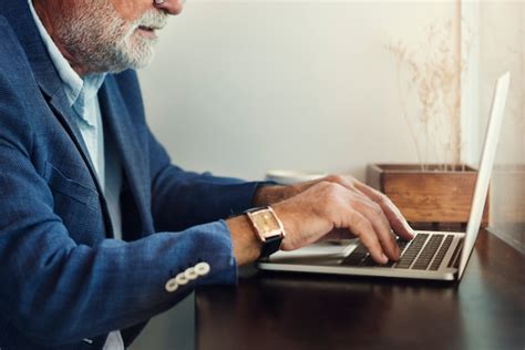Fotografía de un anciano utilizando una tablet o computadora portátil con destreza, simbolizando la adaptación tecnológica