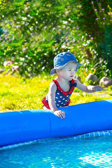 Niña rubia en bikini jugando cerca de la piscina