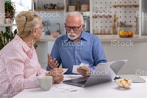 Foto de una pareja de ancianos preocupados con facturas en la mano