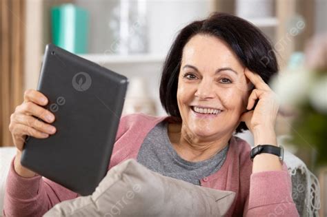 Persona mayor sonriendo mientras usa una tableta para videollamada