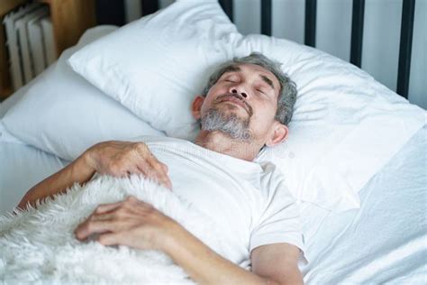 Foto de un adulto mayor cómodamente recostado en una cama clínica con el respaldo ligeramente elevado, leyendo un libro
