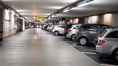 Imagen de un estacionamiento con varios autos y personas cerca de ellos, sugiriendo la presencia de cuidadores en un entorno urbano