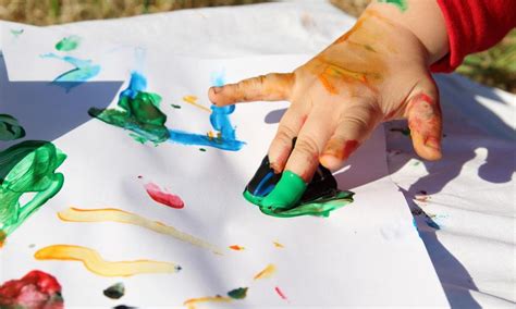 Niños con discapacidad pintando con los dedos sobre una gran hoja de papel. Foto de manualidades con materiales reciclados y alimentos.