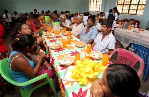 Foto de voluntarios sirviendo comida a adultos mayores en un comedor comunitario