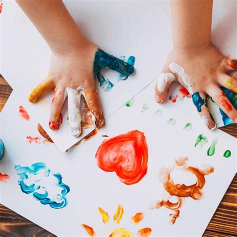 Fotografía de niños con diferentes habilidades haciendo manualidades juntos, pintando con los dedos y usando plastilina
