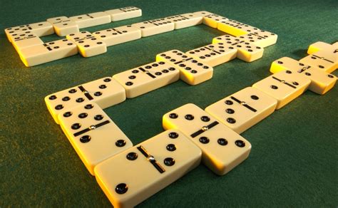Mesa de dominó con fichas en relieve y participantes concentrados
