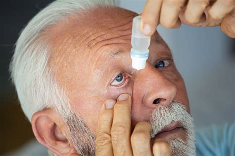 Foto de una persona mayor poniéndose gotas en el ojo después de una cirugía