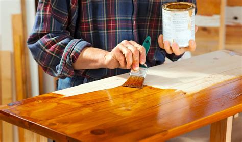 Persona aplicando barniz o pintura a un mueble con una brocha