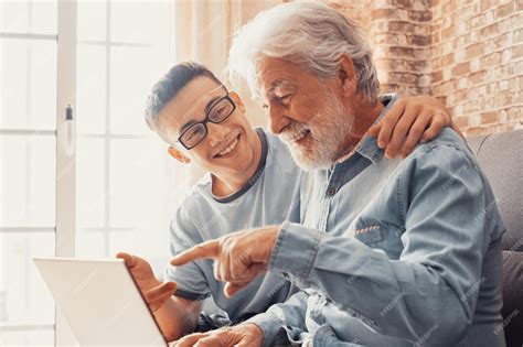 Foto de un nieto ayudando a su abuelo a usar una tablet o computadora
