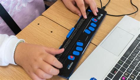 Niño usando una línea Braille conectada a un ordenador