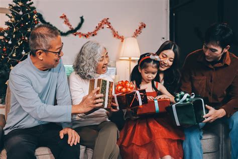 Foto de personas intercambiando regalos, con énfasis en una persona mayor recibiendo un paquete